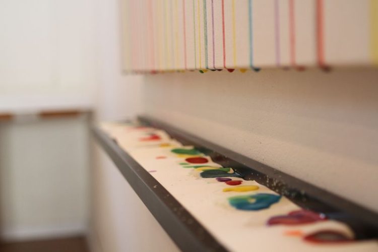 Toile vierge au départ, remplis par des spectateurs de gouttes de peinture qui coulent de haut en bas