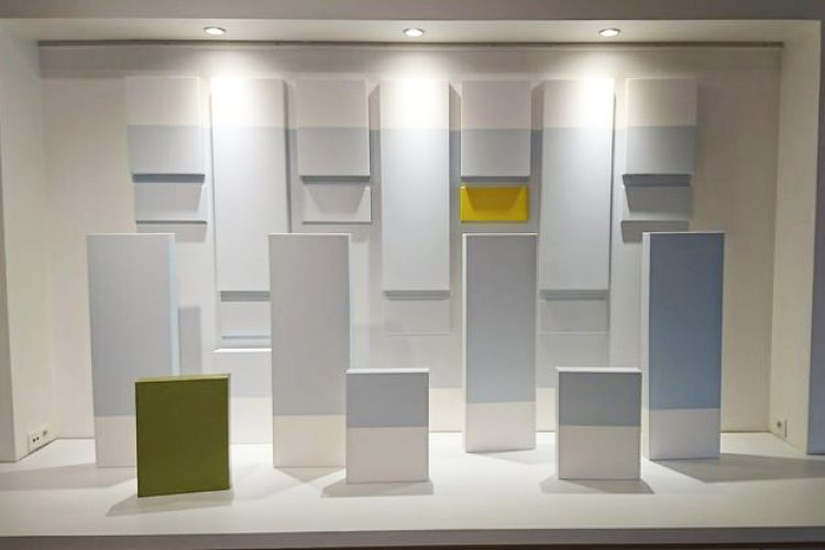 Ensemble de toiles disposées au mur et sur le sol, avec des ton bleu clair, jaune et vert